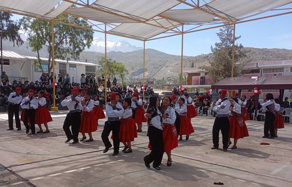 Estudiantes en presentación de danza folclórica tradicional con trajes típicos en el patio institucional