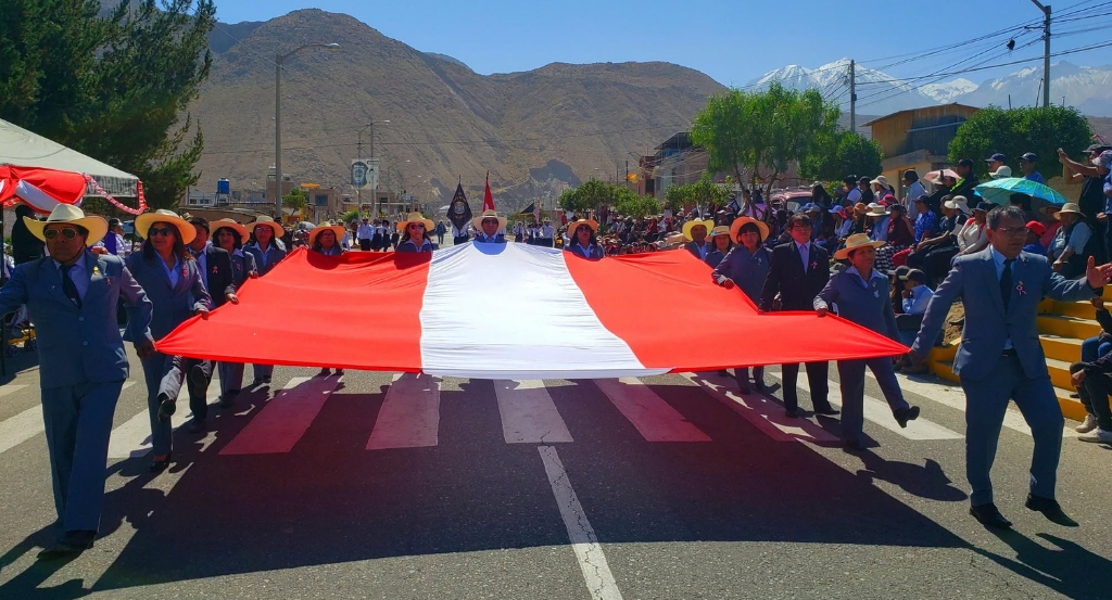 Estudiantes y docentes portando la gran bandera nacional del Perú en el desfile cívico